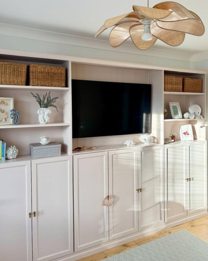 Soft blush painted built-in cabinetry living room media unit from @home.byemily with wicker baskets and minimal decor.