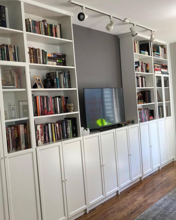 White Billy bookcase media wall with closed doors and open shelves from @yourunclekacie in a living room with natural wood floors and gray accent wall.
