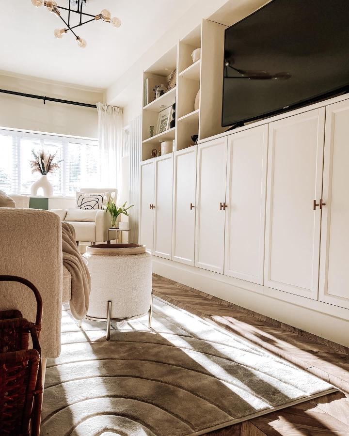 Ivory painted custom cabinetry media wall with open shelves from @thisblackgateshome featuring clean modern style and brass handles.