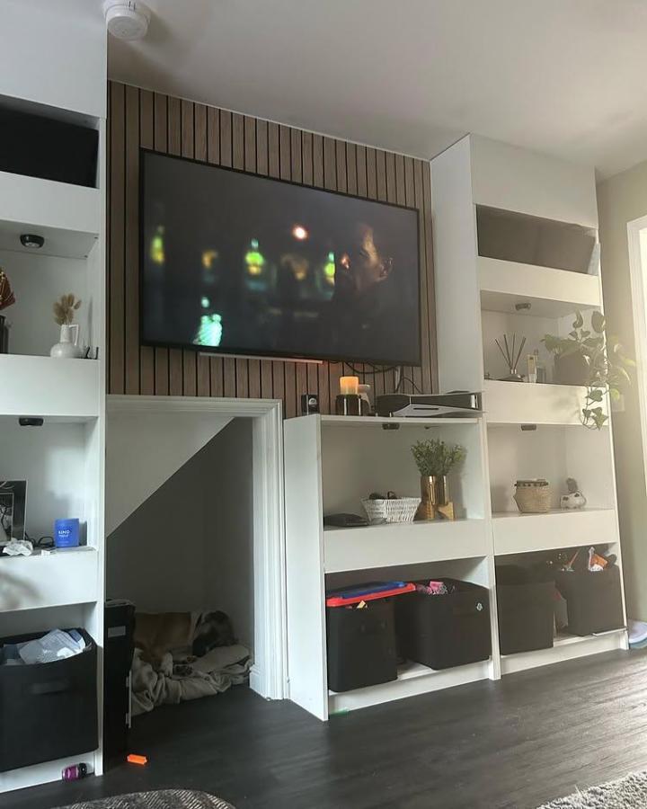 White Billy bookcase media wall with built-in dog nook and dark wood slat backdrop from @ourfergus38 showcasing unique ikea billy bookcase media wall ideas. Stylish and functional.