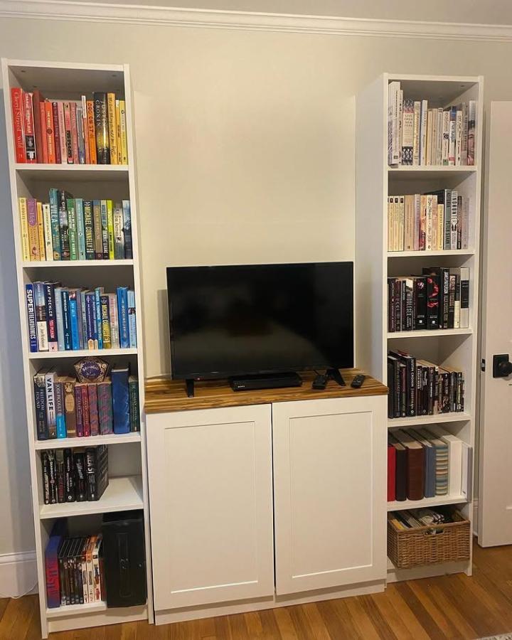 White Billy bookcases with wood top media cabinet from @julzofalltrades. Color coordinated books create a neat and stylish living room focal point.
