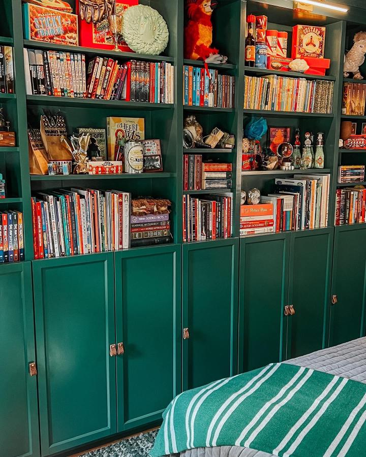 Deep green painted bookcases with leather handles and open shelves filled with books and collectibles from @mandatorydesign. Classic and practical storage solution.