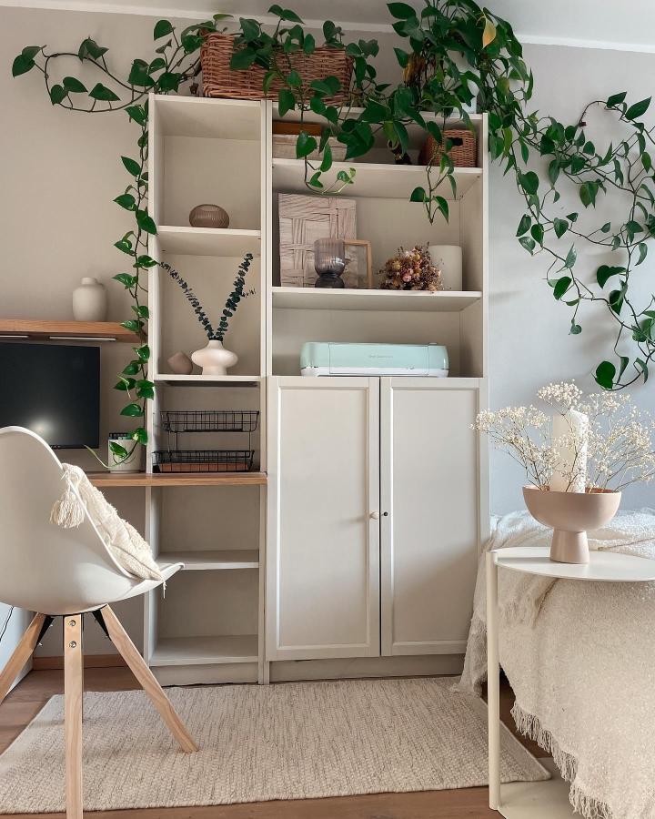 White modular storage unit with trailing plants and natural accents from @cloudis.home. Styled with woven baskets and ceramics in a cozy living space.