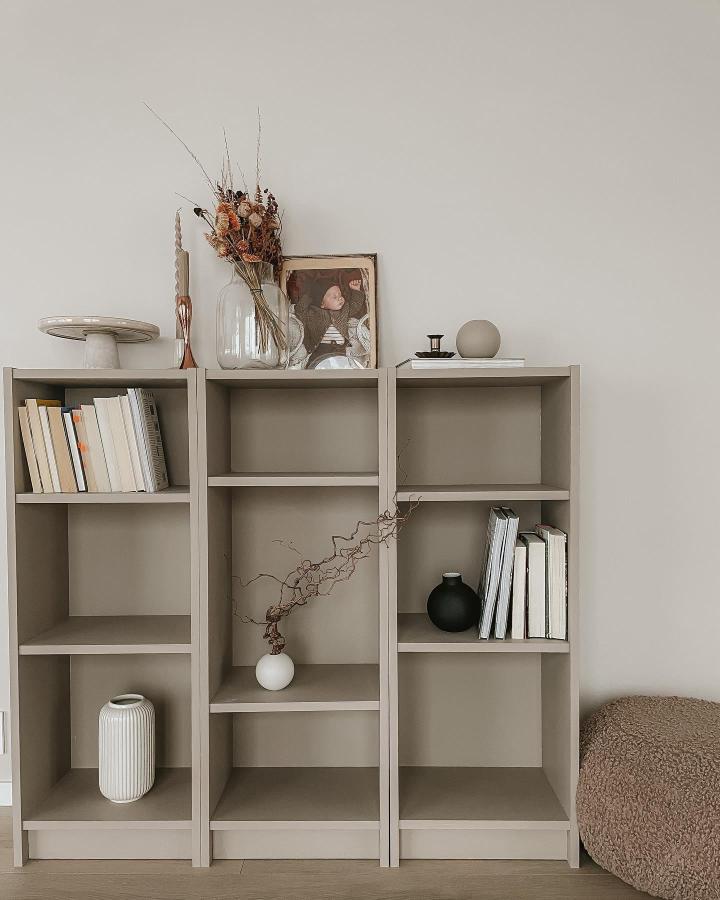 Soft taupe minimalist shelving unit with books and vases by @charlotte.hjornevik featuring neutral tones and natural decor accents.