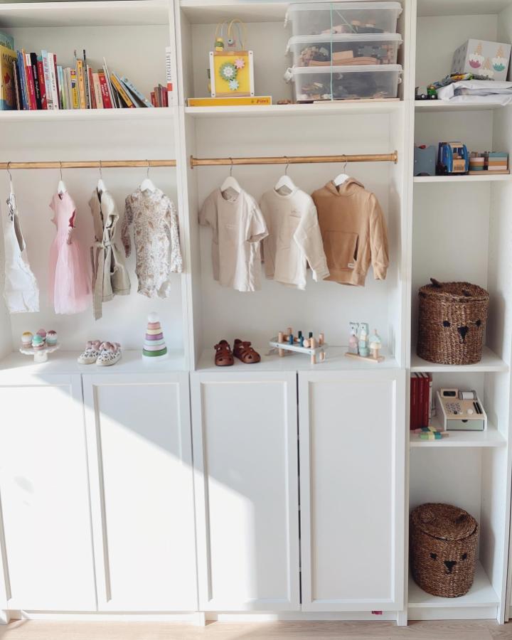 White Billy shelving unit with wooden hanging rods and clear bins by @izabellaamelie. Organized kids’ clothing and toys storage idea.