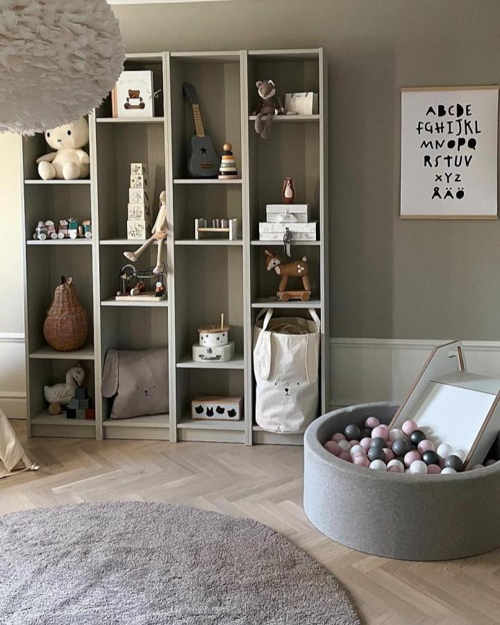 Beige Ikea Billy shelves kids room storage from @kvarteretjollen with soft toys and playful baskets. Calm, neutral and organized space.