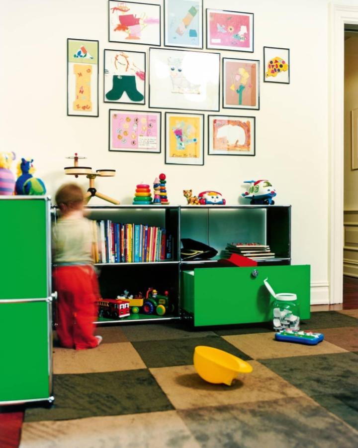 Bright green modular storage unit from @elasticamagazine in a lively playroom with kids’ toys and colorful artwork on walls.