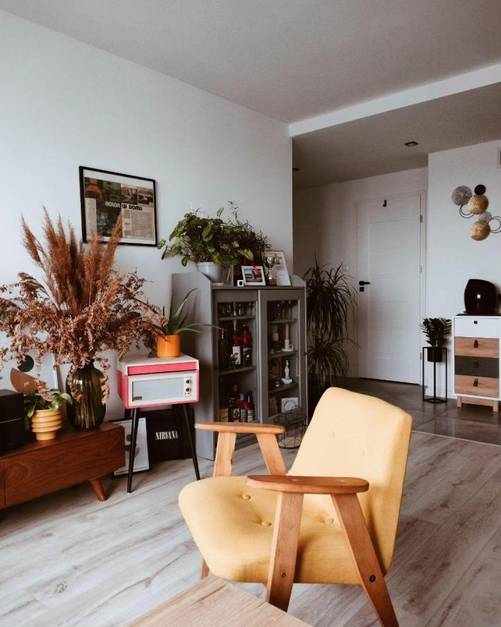 Yellow mid-century style armchair with wooden arms in modern living room by @z_parteru_na_9te featuring natural decor and smart storage solutions.