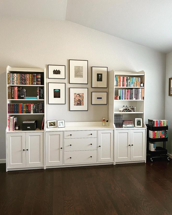 White Hauga cabinets with black knobs and framed artwork in a cozy reading nook by @tara.rreads, clean and inviting storage setup.