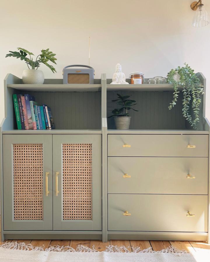 Rattan paneled sage green Ikea Hauga cabinet with gold handles from @decoandhues styled with plants and books. Natural chic storage upgrade.