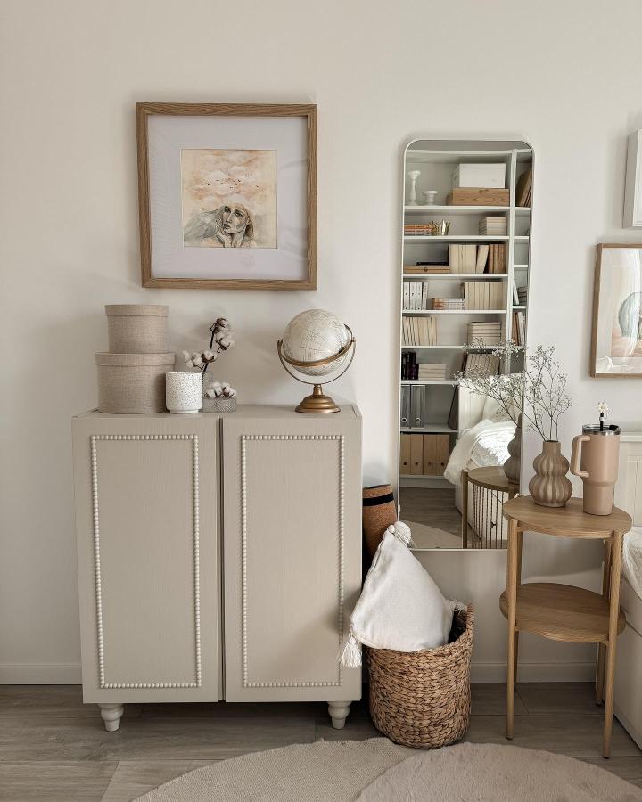 Beige painted wooden cabinet with beaded trim detail in cozy neutral living space by @provinzkindchen, styled with natural textures and warm accents