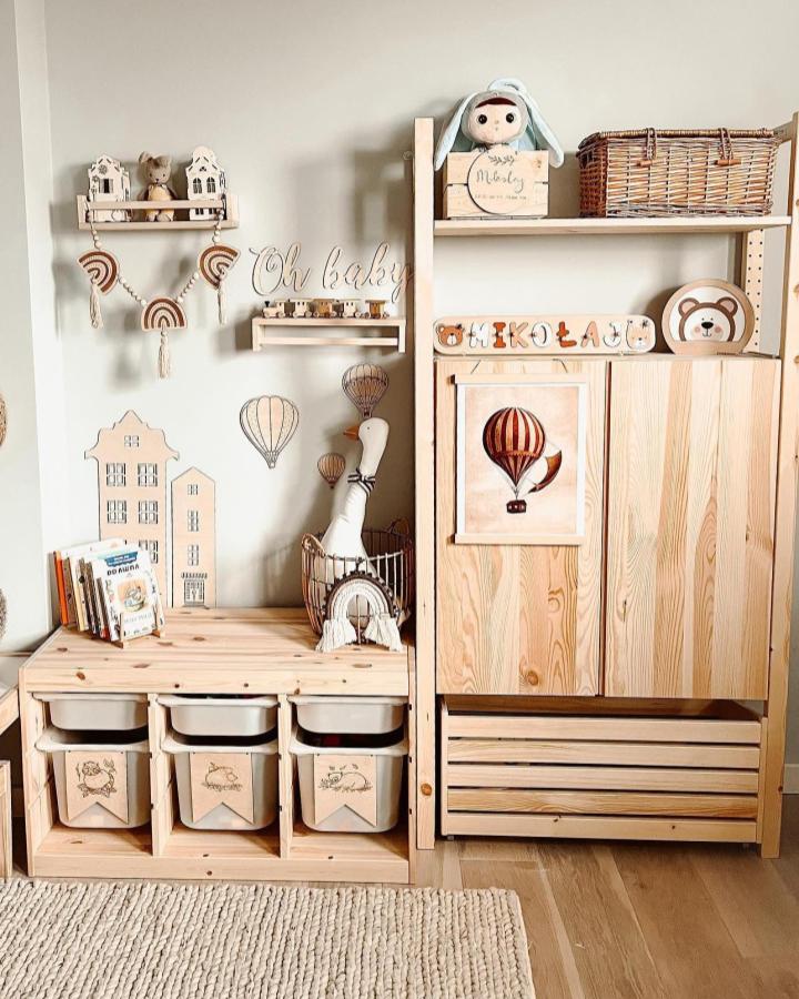 Natural light pine wood kids storage unit by @sachaknight with playful wooden decorations and personalized bins.