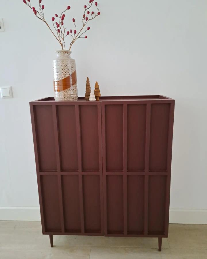 Brown terracotta painted cabinet with vertical grid panels and elevated legs from @villaastrakaani2020. Modern minimalist furniture with warm earthy tones.