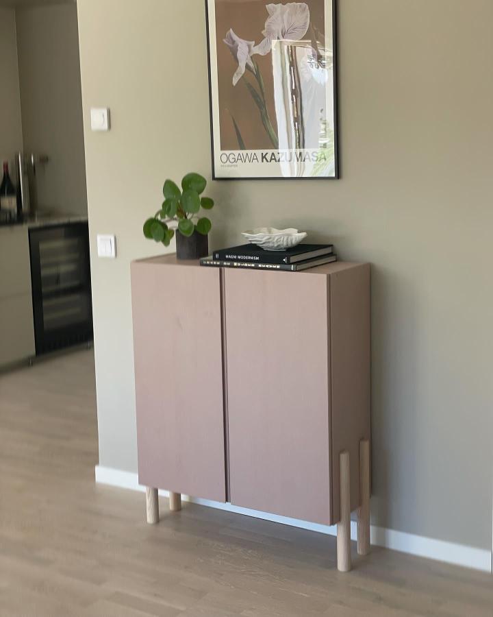 Beige matte cabinet with natural wood legs in a modern living room by @thethirdact.atelier. Simple and elevated design.