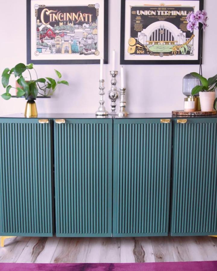 Teal fluted door sideboard with brass accents and mid-century style from @catherineblubaugh in a bright living room setting.
