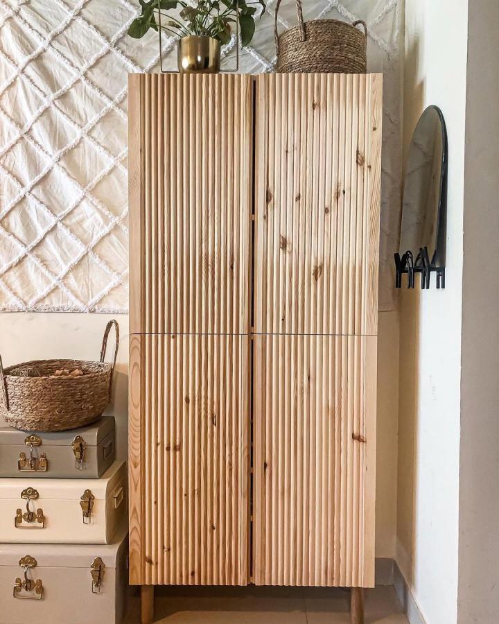 Natural pine fluted door panels on wooden storage cabinet from @house.ofhazel. Vertical grooves add texture to rustic minimal furniture.