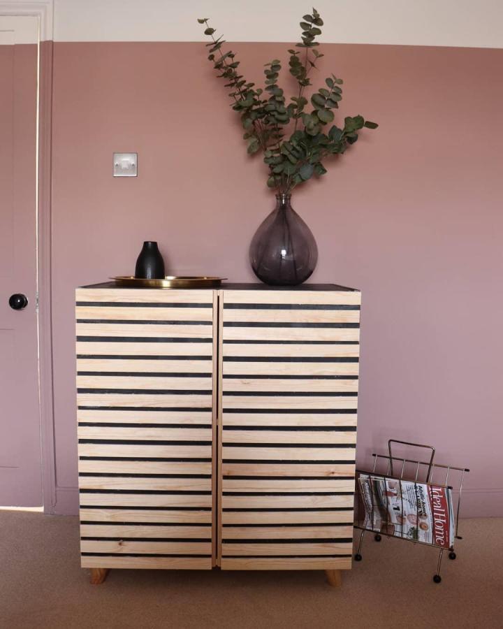 Natural pine strip detailed Ivar cabinet doors with black accents styled in minimal modern room from @hill.home.design_. Rustic and modern blend.
