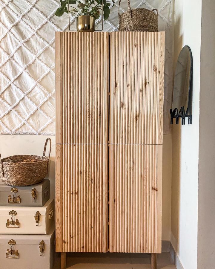 Natural pine wood fluted cabinet with modern legs from @house.ofhazel. Textured door design for stylish storage upgrade.