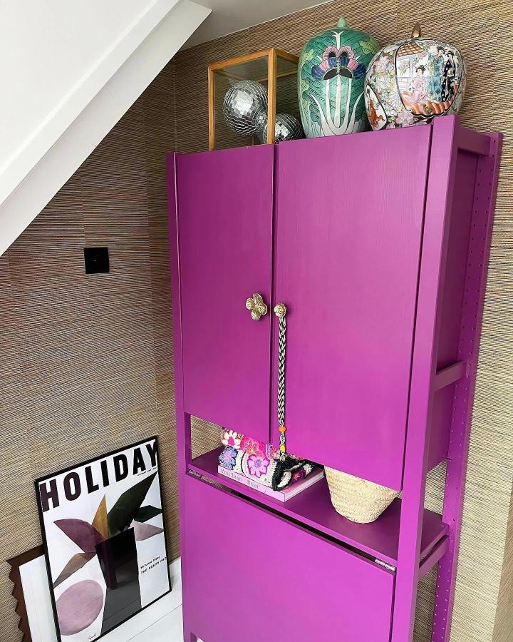 Bold purple painted wooden cabinet with brass flower door handles and open shelf styled by @liefhuisjegroningen. Vibrant and modern storage solution.