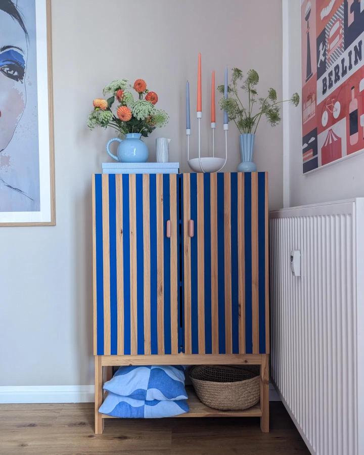 Blue and natural wood striped Ikea Ivar cabinet from @terrazzo.konfetti featuring pink handles and open bottom shelf ikea ivar makeover ideas.