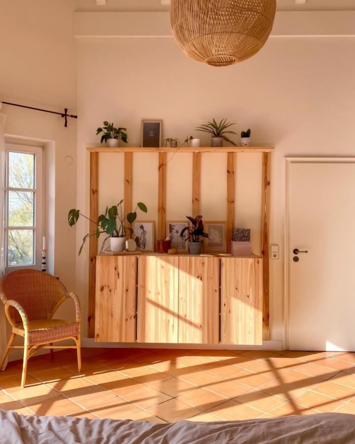 Natural pine wood floating cabinet and open shelving for living room by @couch_magazin. Cozy sunlit minimalist style with plants and art.