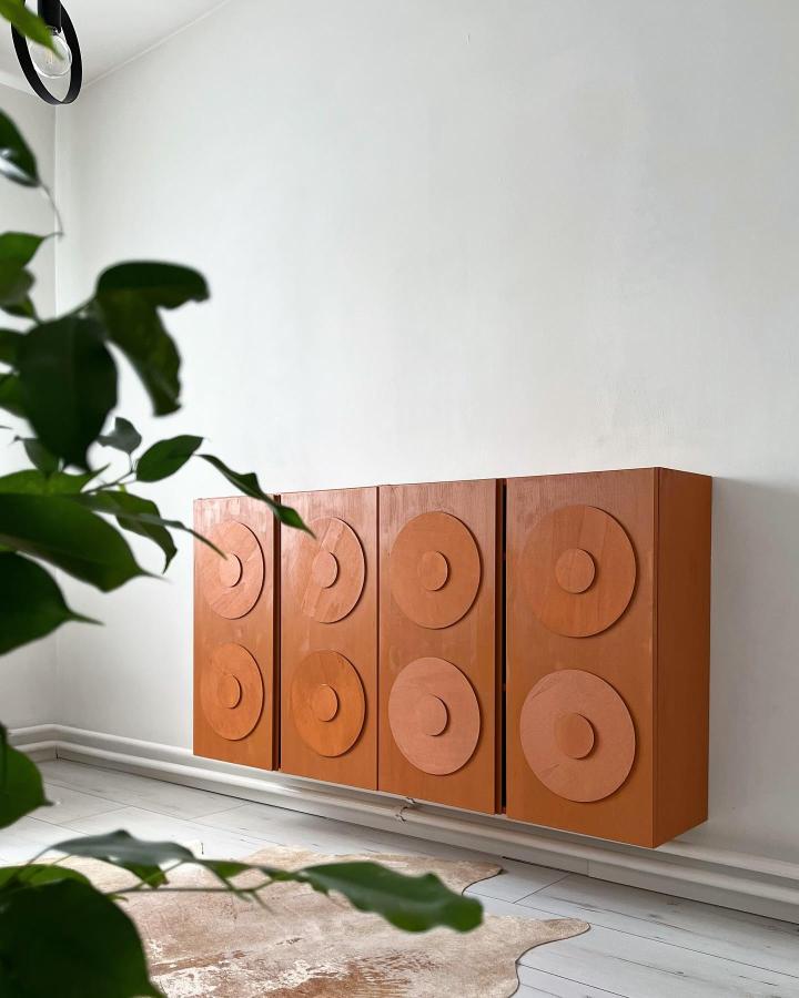 Terracotta wood cabinet with bold circular appliques from @skandi.marti showcasing creative ikea ivar makeover ideas. Modern Scandinavian style.