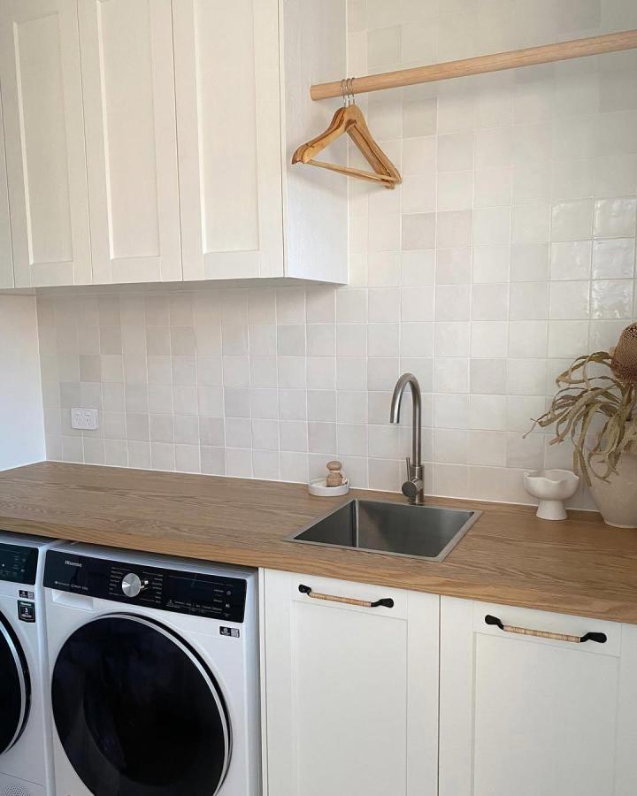 White ENKรPING front cabinets with MรLLEKULLA wood benchtop laundry room design by @reno_bythebay clean and warm aesthetic with subtle black hardware