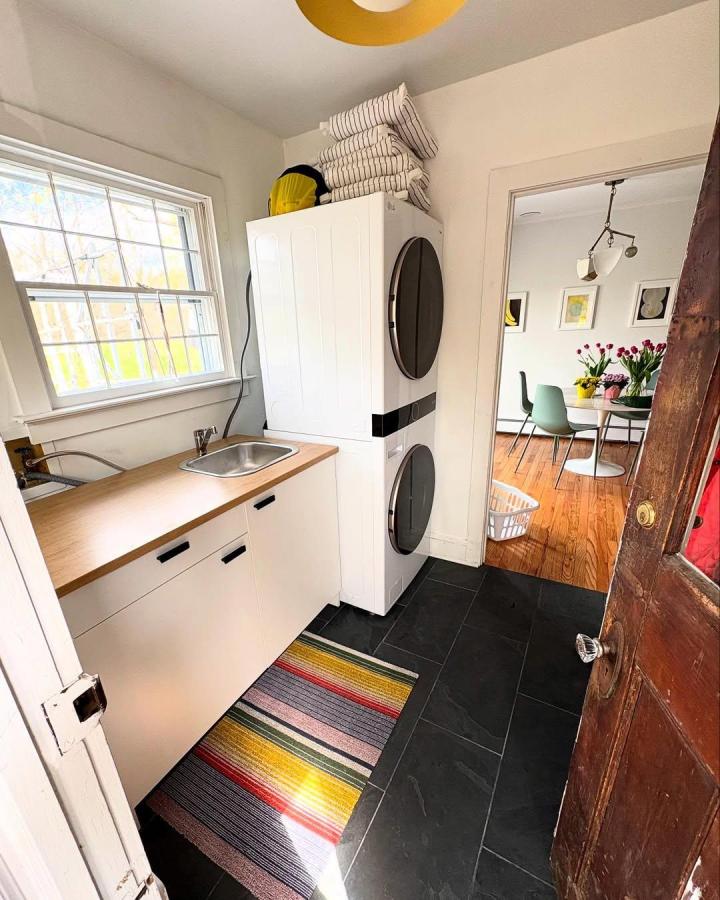 White IKEA cabinet with light wood countertop and integrated sink in laundry room by @racheldoriss. Compact stacked washer dryer and black slate flooring.