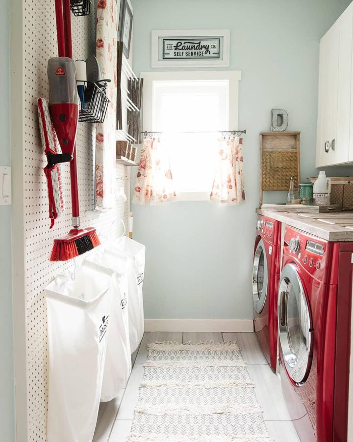 Red front-loaders laundry room with pegboard tools and white IKEA kitchen cabinets from @cozydiyhome bright and tidy laundry space