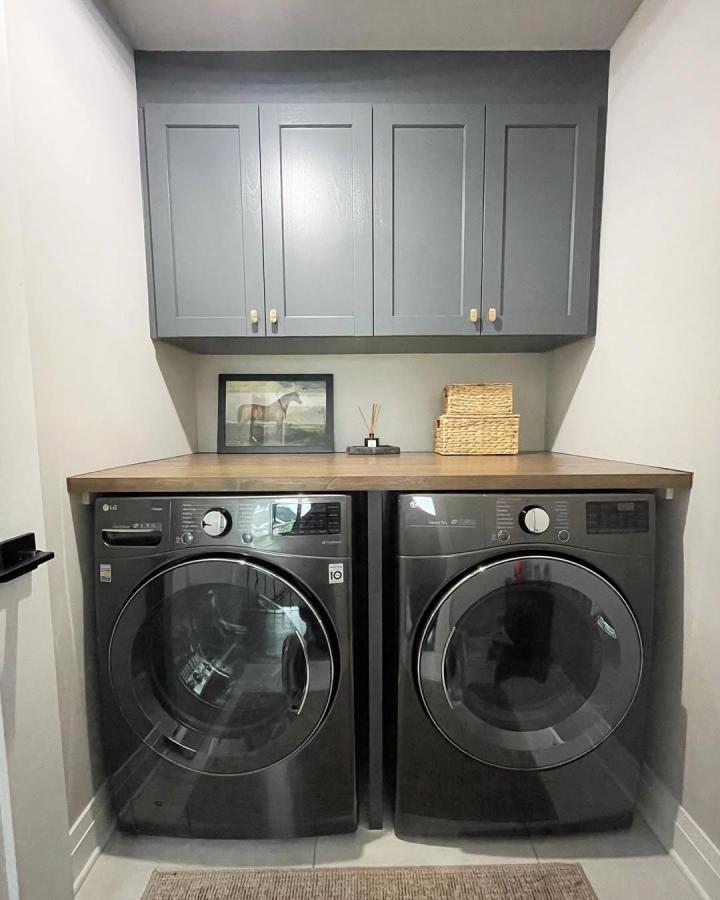 Gray shaker cabinets and warm wood countertop laundry nook setup from @fixitcontracting. Clean, modern, and practical design.
