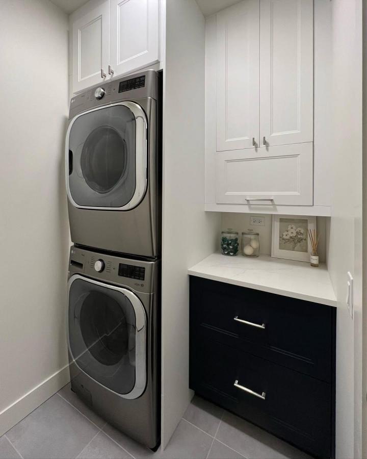 White and navy custom door front cabinetry with stacked washer dryer setup from @ainslie_design_studio in a compact laundry space. Clean, modern look.