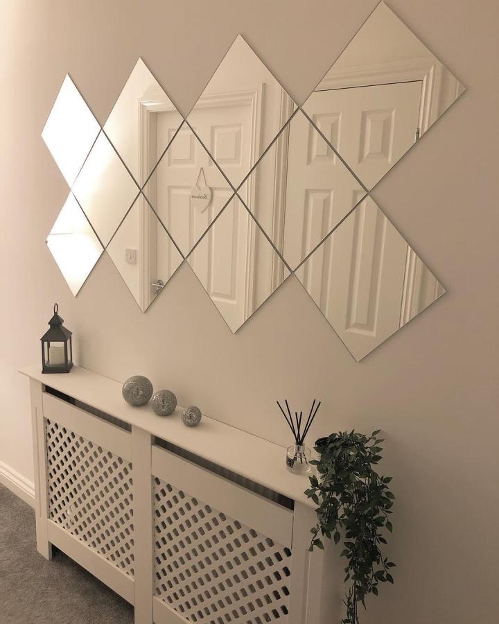 Beige diamond-shaped ikea mirror wall tiles from @homesweethomestagram reflecting a white door and brightening a neutral hallway space.