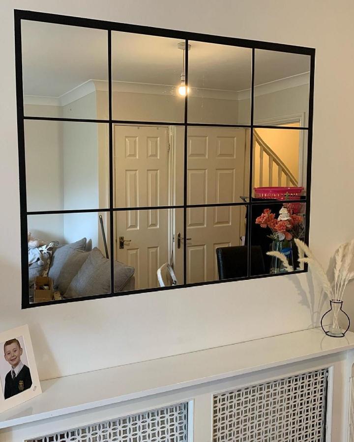 Black grid paneled wall mirror from @life_withemma_. Reflects room depth and adds modern flair with metal framing.