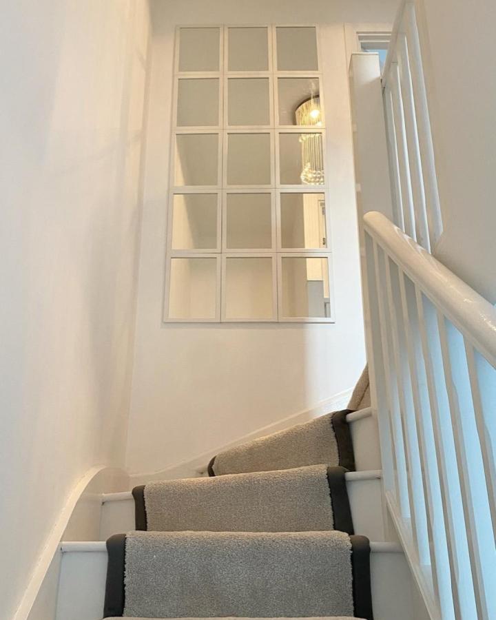 White framed multi-panel mirror wall installation in stairwell from @myhome.byjessica reflecting light and openness.