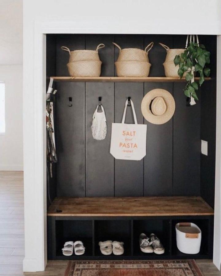 Black paneled mudroom with wooden bench and baskets from @the.orange.home showing ikea mudroom hacks for functional stylish entry storage