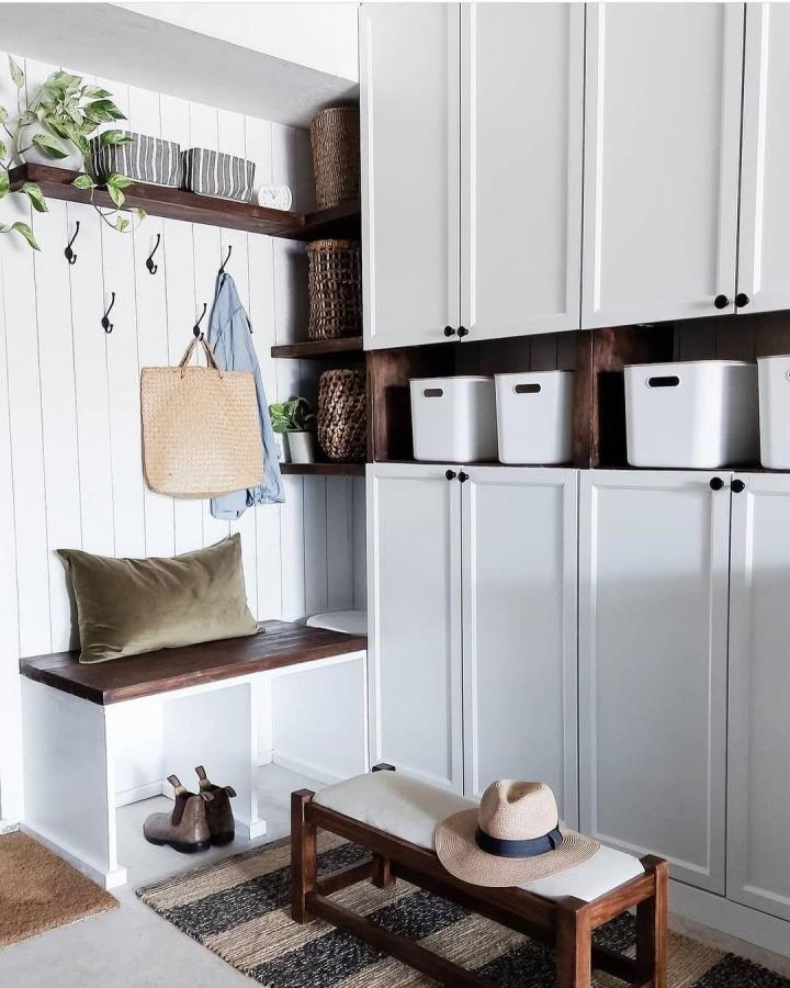 White and dark wood mudroom storage with bench and baskets from @henrikjunehome. Flipped and trimmed IKEA BILLY bookcase revamped with hooks and woven accents.
