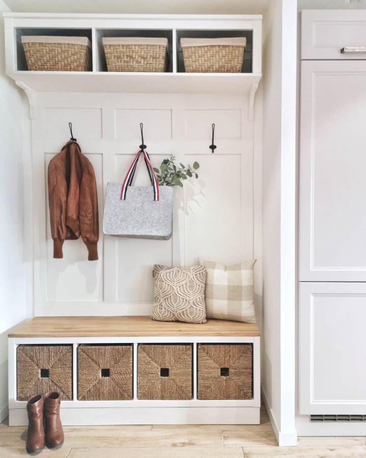 Woven basket storage and white painted KALLAX bench from @chateau.leg0 ikea mudroom hacks with warm wood top and hooks.