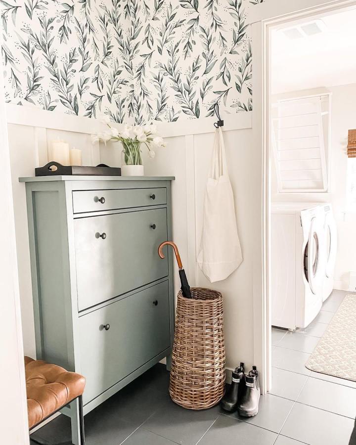 Soft green customized shoe cabinet for compact entryway storage from @everydaygracedesigns with wicker umbrella basket and botanical wall decor