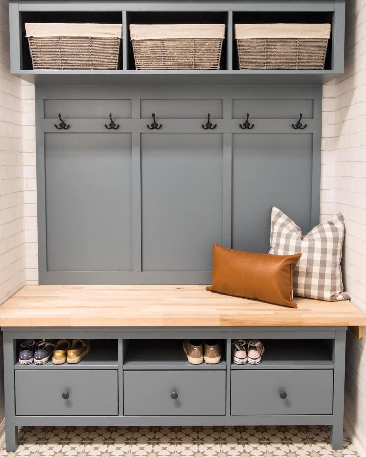 Muted blue-gray painted mudroom bench from @housebyhoff with wooden seat and built-in hooks and storage baskets, stylish entryway solution.
