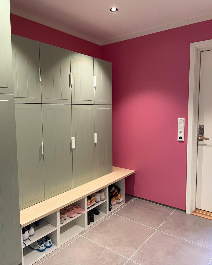 Green METOD kitchen cabinets and natural wood bench mudroom storage by @dortesunivers with open shoe cubbies and vibrant pink wall background.