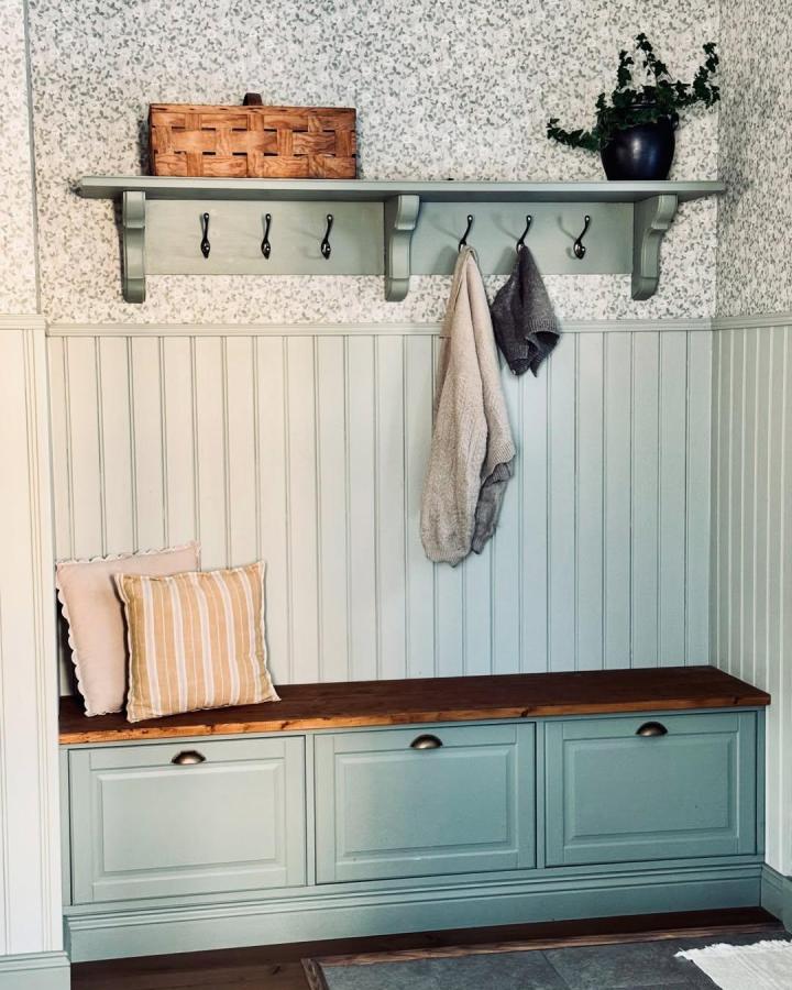 Soft green painted bench with stained wood top and black hooks styled by @krigadal for stylish entryway storage and seating.