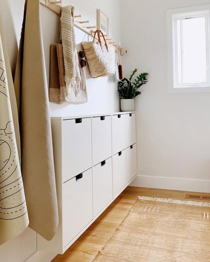 White modern shoe cabinet and wooden wall peg rail from @mysimplysimple. Minimalist mudroom corner with shoe storage and hanging hooks.
