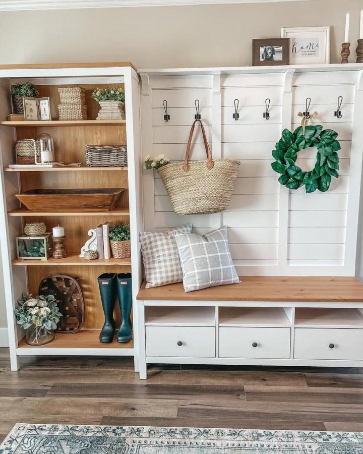 Natural wood and white painted mudroom bench with hooks and storage from @karaahlhensley featuring a shiplap wall and organized shelving.
