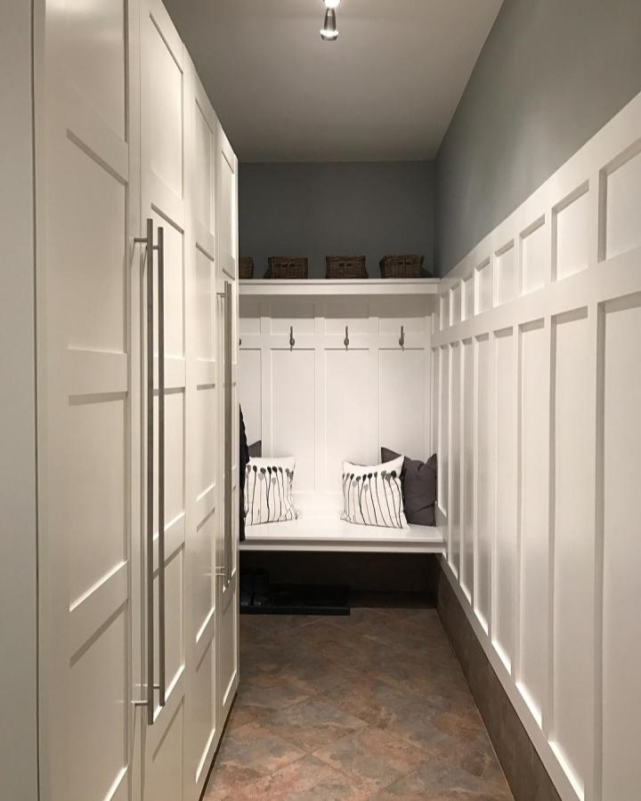 White paneled mudroom with built-in bench and IKEA PAX units from @mg.at.home showing stylish ikea mudroom hacks. Spacious and organized.