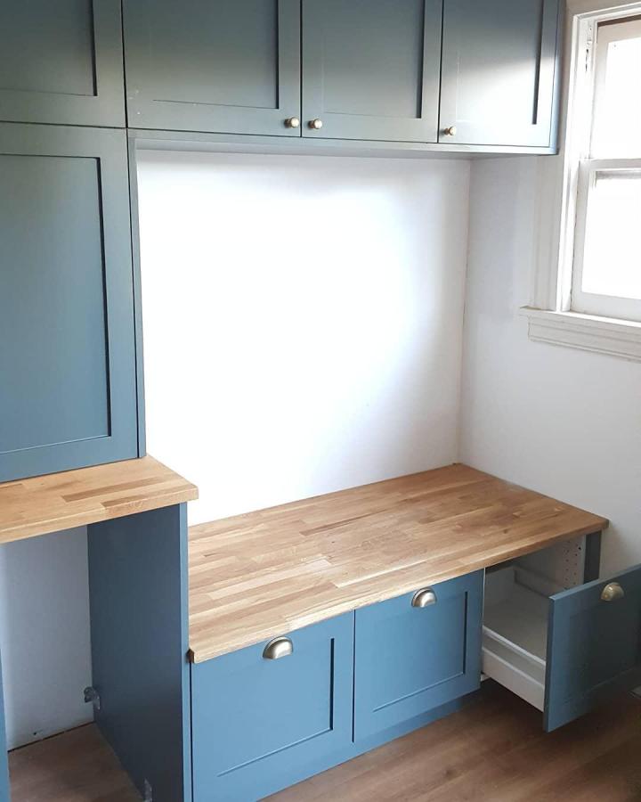 Blue painted cabinet bench with butcher block top and shoe cubbies from @mjlarrabeeinstaller functional entryway storage solution.