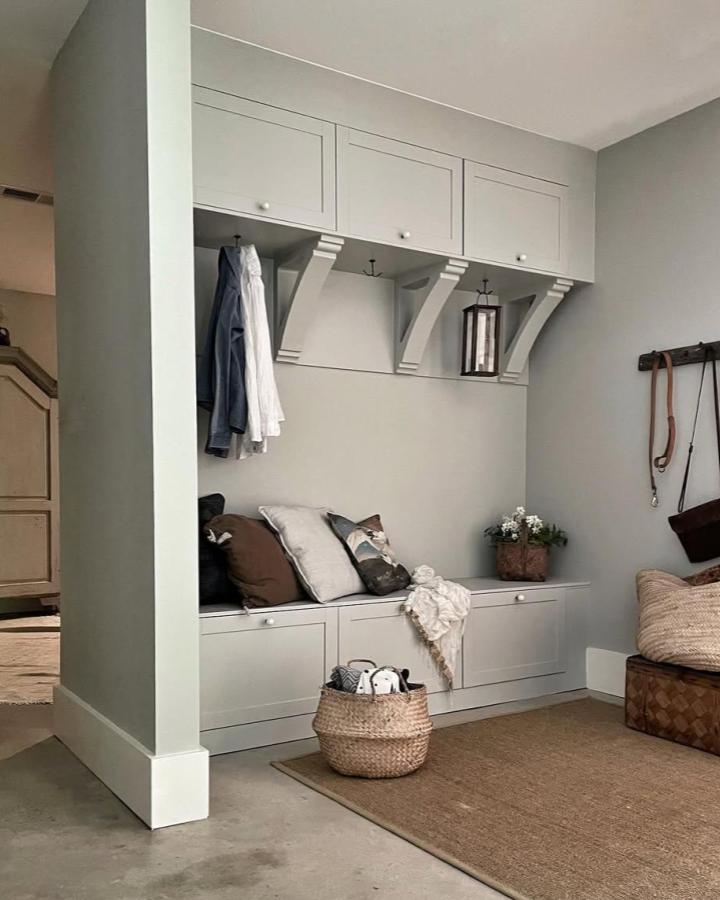 Soft gray built in mudroom bench with storage from @homeathand featuring BESTร
cabinets and classic corbels for organized entryway seating.