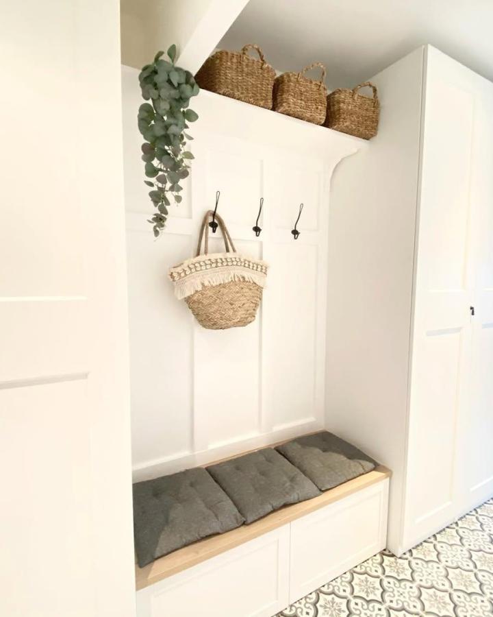 White and wood mudroom bench with gray cushions and wicker baskets by @ginyie Stylish, practical entryway storage solution.