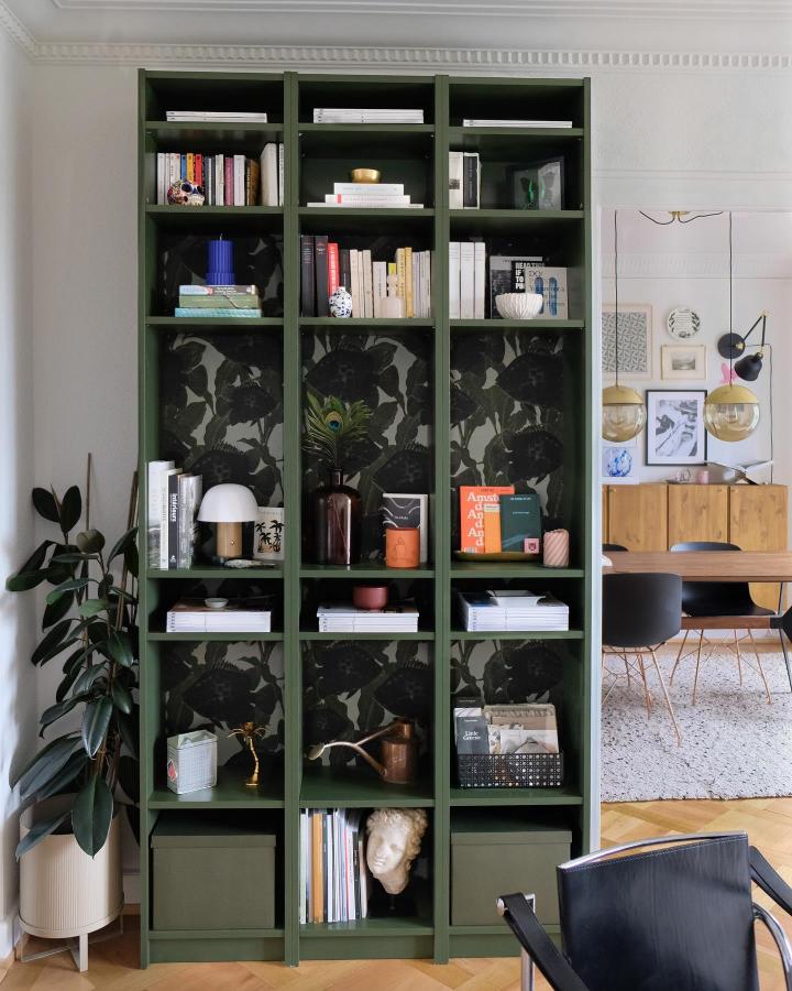 Dark green painted Billy bookcase with black floral wallpaper backing and eclectic decor from @thegempicker creating a stylish home library.