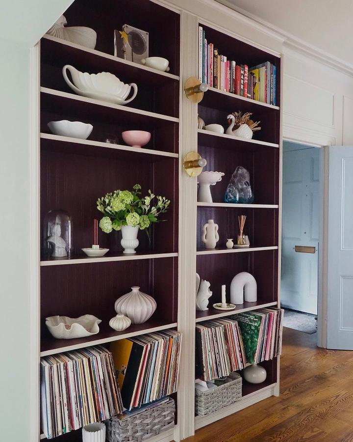 Dark burgundy and cream painted shelving unit in a cozy hallway from @melanielissackinteriors showcasing curated white ceramics and vinyl records.