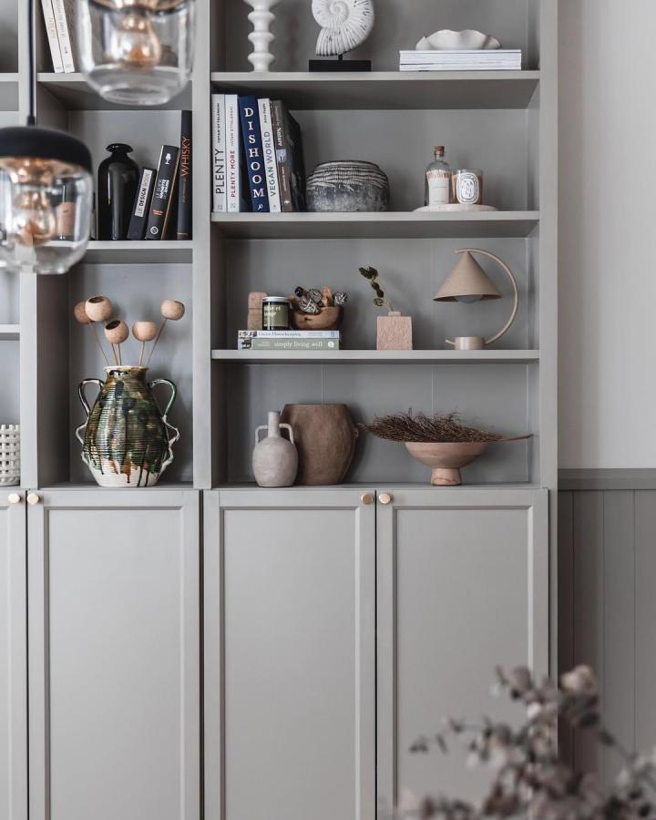 Soft gray painted Billy bookcase with natural ceramic and wooden decor in cozy living room by @byopaline showing calm minimalist style and earthy accents